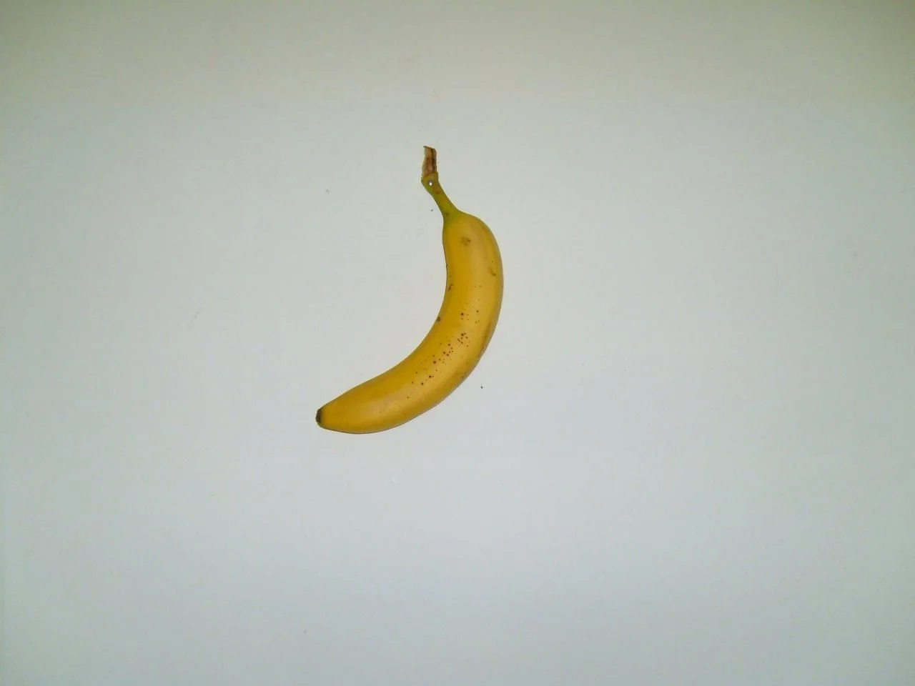 A single banana photographed on a pale background.